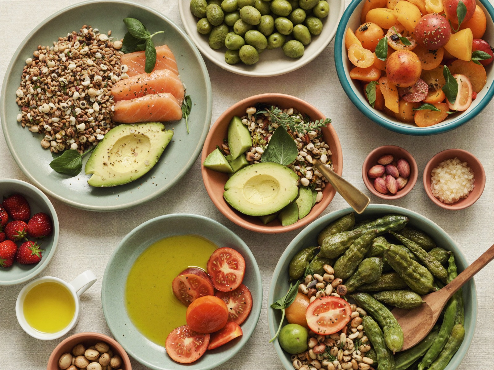 Mesa con preparaciones frescas y coloridas: verduras, frutas, legumbres y granos integrales